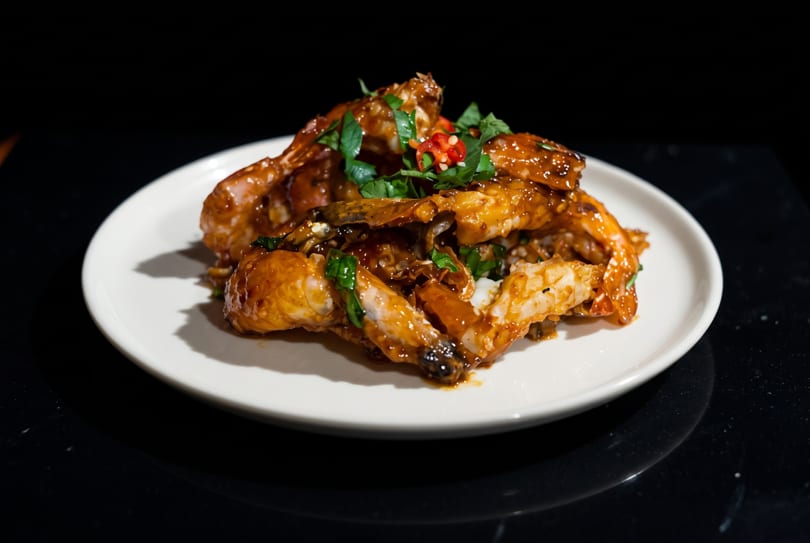 Spicy chili crab dish with fresh herbs and red chilies on a white plate.